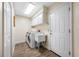 Well-lit laundry room with modern washer and dryer, sink, storage cabinets and wood-look flooring at 5806 Dory Way, Tampa, FL 33615