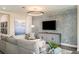 Stylish living room features a modern fireplace, light gray sofa and a circular ceiling light at 10267 Fieldstone Myrtle Way, San Antonio, FL 33576