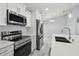 Bright kitchen features stainless steel appliances, white cabinetry, a decorative light fixture and quartz countertops at 104 1St Ne Ave, Lutz, FL 33549