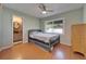 Neutral bedroom with a ceiling fan and wood floors, next to bathroom at 10719 Drummond Rd, Tampa, FL 33615