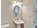 Bright bathroom showcasing a classic pedestal sink, oval mirror and modern lighting at 14733 Gallop Run Dr, Lithia, FL 33547