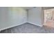 Empty bedroom with neutral colored walls, grey carpet and a hallway view at 14733 Gallop Run Dr, Lithia, FL 33547