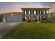 Charming two-story home at dusk with a large front yard, two car garage, and red shutters at 15703 Jericho Dr, Odessa, FL 33556