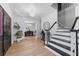 Light-filled foyer featuring sleek hardwood floors, black and white staircase, and views of living spaces at 15703 Jericho Dr, Odessa, FL 33556