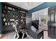 Elegant home office with black built-in shelves, desk, blue accent wall, and open to living space at 15703 Jericho Dr, Odessa, FL 33556
