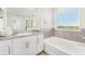 Bright bathroom with a granite countertop vanity, a large window, and a soaking tub at 16946 Oval Rum Dr., Wimauma, FL 33598