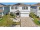 Two-story home featuring a manicured lawn and garden, paved driveway, and two-car garage at 16946 Oval Rum Dr., Wimauma, FL 33598