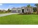 Inviting single-story home with a lush green lawn, gray driveway, and stone facade details at 24041 Peppercorn Rd, Punta Gorda, FL 33955