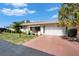 Charming single-story home featuring a red driveway, lush lawn, and mature palm trees under a clear blue sky at 312 Fairside Ct # 12, Sun City Center, FL 33573