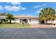 Quaint single-story home with a red driveway, manicured lawn, and mature palm trees on a sunny day at 312 Fairside Ct # 12, Sun City Center, FL 33573
