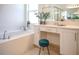 Relaxing bathroom featuring a soaking tub under a window and vanity area with seating at 32768 Tree Of Life Ave, Wesley Chapel, FL 33543