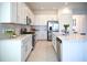 Modern kitchen boasts white cabinets, stainless steel appliances, a gas range, and a large island with bar seating at 32768 Tree Of Life Ave, Wesley Chapel, FL 33543