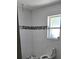 White-tiled bathroom featuring a modern design, a decorative mosaic band, and a bright window, showcasing a clean aesthetic at 3936 48Th S Ave, St Petersburg, FL 33711