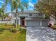 Home exterior with mature landscaping, gray paint, large driveway, and a 3-car garage at 4859 Augusta Ave, Oldsmar, FL 34677