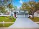 Home exterior with gray paint, lush landscaping, driveway, and a 3-car garage at 4859 Augusta Ave, Oldsmar, FL 34677