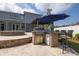 Outdoor kitchen with built-in grill, mini fridge, bar seating, travertine tile, and view of fire pit at 4859 Augusta Ave, Oldsmar, FL 34677
