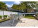 Outdoor patio with travertine tile, outdoor dining table, and white vinyl fence surrounding the backyard at 4859 Augusta Ave, Oldsmar, FL 34677