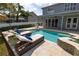Backyard swimming pool with travertine pavers, lounge chairs and landscaping, and view of the house at 4859 Augusta Ave, Oldsmar, FL 34677