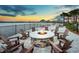 Outdoor fire pit area with rocking chairs, overlooking a lake and lounge chairs with umbrellas for an evening under the stars at 5014 Coastal Oak Ct, Lakewood Ranch, FL 34211