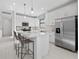 Bright, white kitchen with a stainless steel refrigerator, kitchen island and three bar stools at 5014 Coastal Oak Ct, Lakewood Ranch, FL 34211