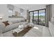 Bright living room featuring a gray sofa, glass coffee table, and sliding glass doors leading to the outdoor area at 5014 Coastal Oak Ct, Lakewood Ranch, FL 34211