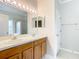 Bathroom featuring dual sinks, wood cabinets, large mirror and vanity lighting at 6328 Desert Peace Ave, Land O Lakes, FL 34639