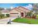 Charming single-story home featuring a two-car garage and well-maintained front yard with green grass and landscaped flowerbeds at 6328 Desert Peace Ave, Land O Lakes, FL 34639