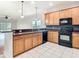 Spacious kitchen featuring wood cabinetry, black appliances, breakfast bar, and open layout with tile flooring at 6328 Desert Peace Ave, Land O Lakes, FL 34639
