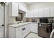 Well-organized laundry room with white cabinetry, a utility sink, and modern stainless steel appliances at 7226 Bryce N Pt, Pinellas Park, FL 33782