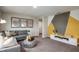 Comfortable living room with a sectional sofa, stylish decor, and a striking geometric accent wall at 7647 Peace Lily Ave, Wesley Chapel, FL 33545
