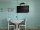 Cozy dining area featuring a white table with two chairs and a wall-mounted television at 8567 W Gulf Blvd # 17N, Treasure Island, FL 33706