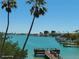 Scenic waterfront view features a dock, lush palm trees, and the nearby city skyline at 8567 W Gulf Blvd # 17N, Treasure Island, FL 33706