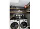 Well-organized laundry room featuring front loading washer and dryer, shelving, and decor at 8713 Hampden Dr, Tampa, FL 33626