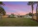 Sprawling backyard featuring a covered patio area, lush green grass, palm trees, and privacy fencing at 1003 39Th Ne Ave, St Petersburg, FL 33703