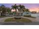 Quaint single-story home with a circular driveway, lush greenery, and a welcoming facade at dusk at 1003 39Th Ne Ave, St Petersburg, FL 33703