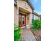 A welcoming red front door with decorative glass, complemented by lush plants and a stone bench at 10213 Saint Francis Ter, Palmetto, FL 34221