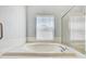 A sun-drenched bathtub next to window and glass enclosed shower creates a relaxing retreat at 10810 Moss Island Dr, Riverview, FL 33569