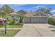 Charming home featuring a well-manicured lawn, lush landscaping, and an attached three-car garage at 10810 Moss Island Dr, Riverview, FL 33569
