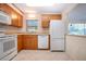 Functional kitchen with wood cabinets, white appliances, tile floors, and a pass-through window for easy serving at 1730 W Del Webb Blvd, Sun City Center, FL 33573
