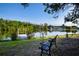 Beautiful lake view showcasing a peaceful pond, a quaint dock, and a tranquil setting with lush greenery and a comfortable bench at 1730 W Del Webb Blvd, Sun City Center, FL 33573