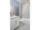 Well-lit bathroom with blue accent wall, white vanity, decorative mirrors, and shower with tile surround at 17420 Moonflower Dr # 202, Venice, FL 34293