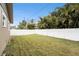 Fenced backyard with green lawn, mature landscaping, and a sunny sky at 1819 Shore Acres Ne Blvd, St Petersburg, FL 33703