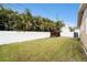 Wide shot of a fenced backyard with lush lawn, utility shed, and tropical foliage at 1819 Shore Acres Ne Blvd, St Petersburg, FL 33703