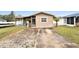 Tan one-story house with a covered porch, small front yard, and a concrete driveway at 1819 Shore Acres Ne Blvd, St Petersburg, FL 33703
