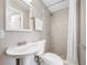 Bathroom with pedestal sink, toilet, vanity mirror, and a walk-in shower at 217 Emerald Ln, Largo, FL 33771