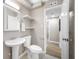 Clean bathroom with pedestal sink, toilet, vanity mirror, and a door to a hallway at 217 Emerald Ln, Largo, FL 33771