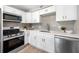 Modern kitchen with white cabinets, stainless steel appliances, and a gray tiled backsplash at 217 Emerald Ln, Largo, FL 33771