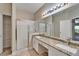 Bathroom featuring a dual sink vanity with granite countertops and a glass-enclosed shower at 2222 Mayfield Palms Ln # 322, Sun City Center, FL 33573