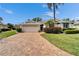 Inviting home featuring a lush lawn, colorful landscaping, and a brick driveway at 2222 Mayfield Palms Ln # 322, Sun City Center, FL 33573