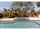 Relaxing outdoor swimming pool with built in spa features a stone patio, and is surrounded by green grass and palm trees at 244 43Rd Ave, St Pete Beach, FL 33706